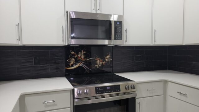 black backsplash with white cabinets glass flower accent piece over range