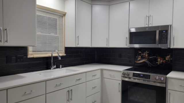 black subway tile backsplash with white cabinets and glass flower accent tile over oven range
