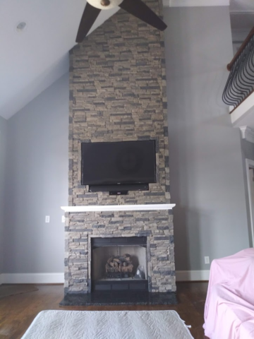faux fake stone chimney fireplace living room with white mantle trim and TV