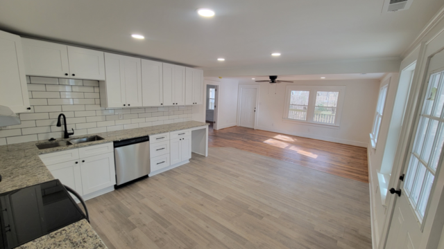 finished custom kitchen with white cabinets black hardware polished granite countertops and hardwood floors white walls
