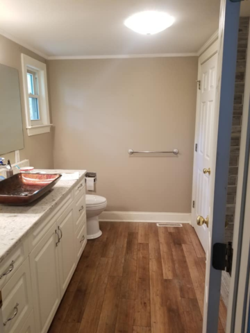 new bathroom with dark laminate LVP flooring white vanity sink and custom tile shower
