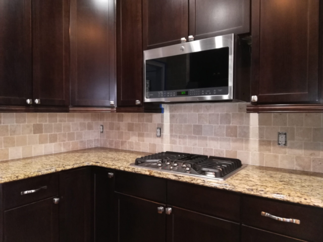 neutral tile backsplash finished wood dark cabinets stainless appliances microwave